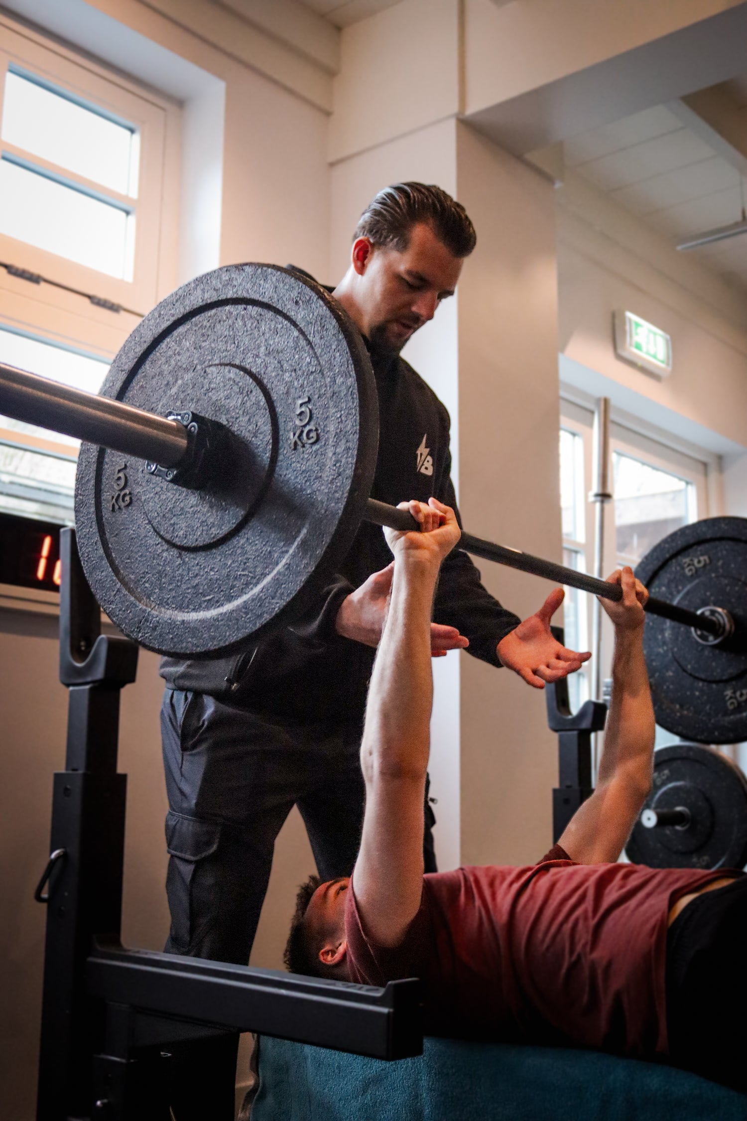 Boas helpt een man die leert om te bankdrukken met tips, uitleg over de houding en de juiste techniektraining